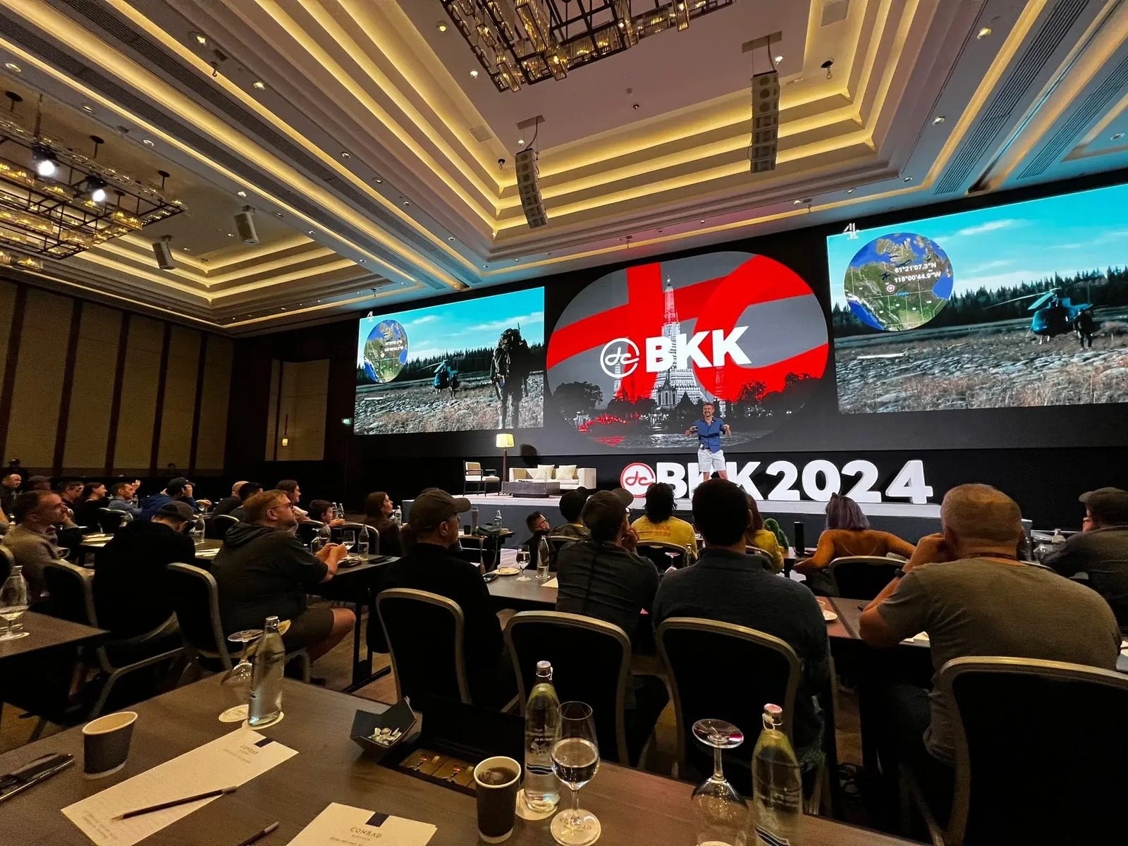 Tom Williams presenting on a large stage to a seated audience at the BKK 2024 conference.
